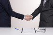 two men in suits shake hands after signing the contract