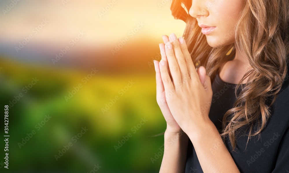 A young beautiful  girl praying on blurs background - obrazy, fototapety, plakaty 