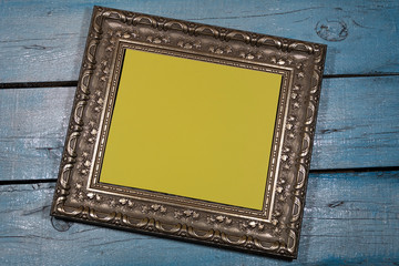 Background, texture. Close-up. A wide silver frame for antique paintings with a yellow middle is located at an angle on a painted wooden background.