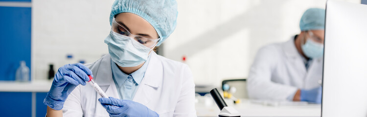 panoramic shot of molecular nutritionist holding test tube in lab