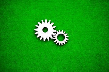 A pair of wooden gears on a green background. mechanism, interaction, movement.