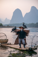 A fisherman and his cormorants on a raft in sunset