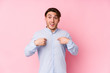 © Asier - Young caucasian man posing in a pink background isolated surprised pointing with finger, smiling broadly.