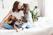 © Drobot Dean - Loving couple indoors at home play on guitar.
