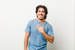 © Asier - Young handsome man against a white background laughs out loudly keeping hand on chest.