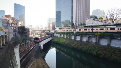 Canvas Print - Train passing on the bridge in the Tokyo city across the bridge and city view in the background.Tokyo's train/subway train moving in city center of Tokyo.Tokyo Olympic 2020 4K UHD video transportation
