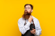 © luismolinero - Barber with long beard in an apron over isolated yellow background