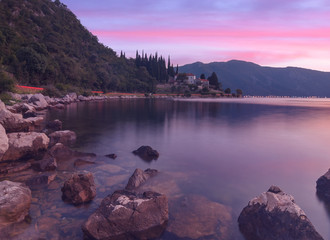 Wall Mural - Beautiful sunset on the beach in Montenegro with long exposure effects in the sea. Beach landscape with city lights in the background.