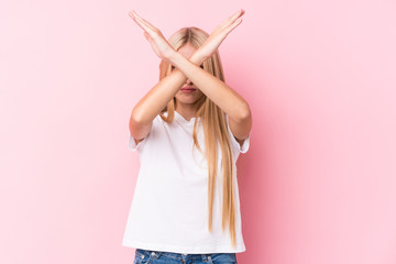 Young blonde woman on pink background keeping two arms crossed, denial concept.