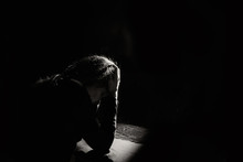 Lonely And Sad Girl Holding Her Head On A Black Background
