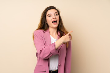 Wall Mural - Young brunette girl with blazer over isolated background surprised and pointing side