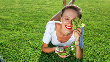 beautiful caucasian woman eating salad over green natural background