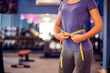 © Aleksej - Woman measuring waist with meter in the gym. People, fitness and health concept