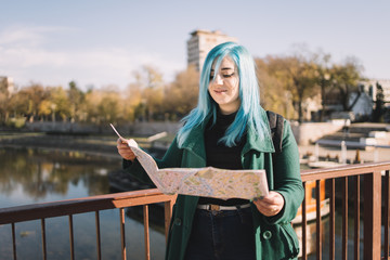 Smiling girl holding opened map on bridge