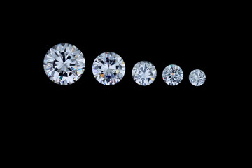 Wall Mural - A row of five round faceted diamonds going from smallest to largest sits on a black background.