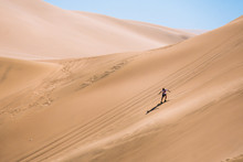 Silhouette Of Man Practice Sandboarding In The Desert Of Peru.