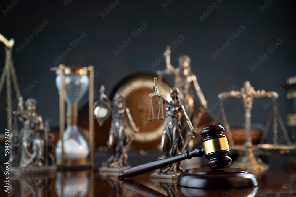 Law and justice theme. Judge’s gavel, Themis statue,  scale, hourglass and old clock on the shining wooden brown table and the gray background. - obrazy, fototapety, plakaty 