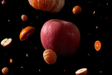 Apples And Oranges Suspended In Front Of A Black Background To Simulate The Space Form Of The Universe