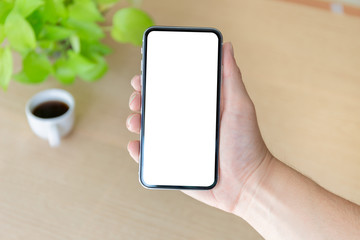 Mockup image blank white screen cell phone.man hand holding texting using mobile on desk at coffee shop.background empty space for advertise text.people contact marketing business,technology 