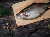 Fototapeta Tęcza - fresh trout on a Board on a wooden table for cooking. Raw red fish