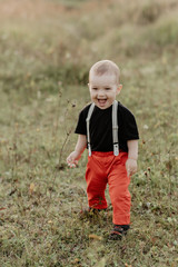 little baby boy smiling standing on grass in summer field