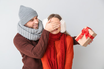 Wall Mural - Happy man giving present to his girlfriend against light background