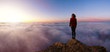Adventurous Girl on a Rocky Mountain Peak above the Clouds enjoying the beautiful view of the Colorful Sunset or Sunrise. Image Composit. Adventure, Travel, Explore Concept.