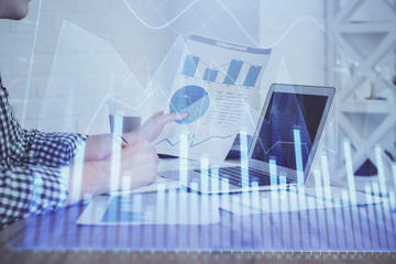 Multi exposure of financial graph with man works in office on background. Concept of analysis.