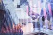 © peshkova - Double exposure of graph with man typing on computer in office on background. Concept of hard work. Closeup.