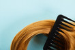 Top view of comb in brown hair on blue background