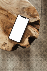 blank screen smartphone with empty copy space mockup on solid wooden stool and carpet. flat lay, top