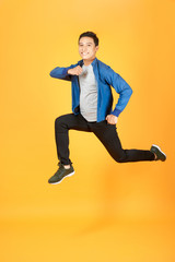 Wall Mural - Young happy Asian teen jumping welcomely isolated on orange studio background