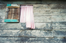 Weathered Wood Shack Background With Pink Curtain Billowing Out An Open Window
