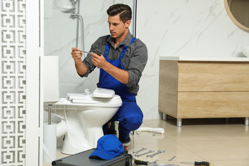 Canvas Print - Professional plumber working with toilet bowl in bathroom