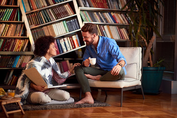 Couple having fun in room with book and coffee