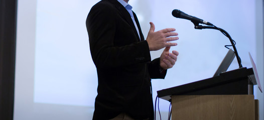 Fototapete - Seminar presenter at corporate conference giving speech. Speaker giving lecture to business audience. Executive manager leading discussion in hall during company training event. 