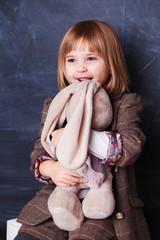 cute happy little girl hugging her toy rabbit