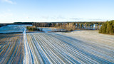 Fototapeta Miasto - Aerial view over snowy winter landscape with the fields, forest and frozen lake Hino in Võru county, Southern Estonia