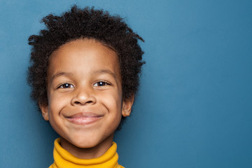 Wall Mural - Smiling kid boy portrait. Little african american child boy on blue background