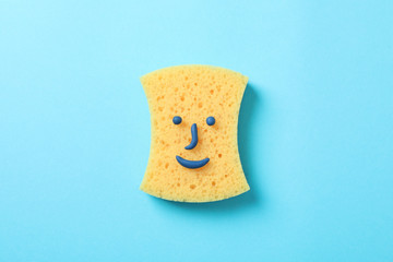 Sponge with smiley face on blue background, top view