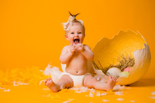 Baby Girl In A Chicken Costume With Feathers And Easter Eggs On A Yellow Background, Space For Text. The Concept Of Easter