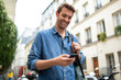 © mimagephotos - older guy walking in city looking at cellphone