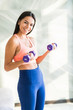 © F8  \ Suport Ukraine - Young beauty woman is exercising with dumbbells at home. Fitness, workout, healthy living and diet concept.