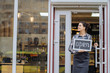 © Iryna - Beautiful asian woman store owner with standing in the doorway of her coffee shop looking at camera and smiling.Portrait of girl waitress wearing apron and standing in front