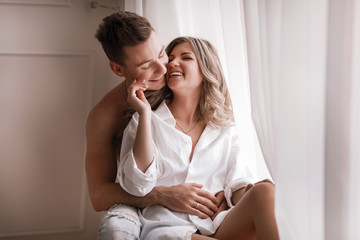 loving couple having fun together at home, playful wife biting smiling husband ear, piggyback, man a