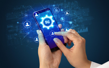 Female hand holding smartphone with 5G abbreviation, modern technology concept