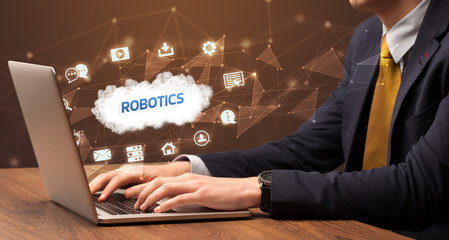 Businessman working on laptop with ROBOTICS inscription, modern technology concept
