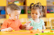 © Oksana Kuzmina - Toddlers boy and girl playing at table with educational toys. Children infants in creche or daycare.