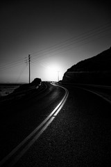 Wall Mural - greyscale of a curvy road surrounded by hills under sunlight