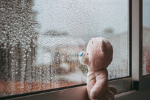 A Toy Pink Sad Bear Is Looking Out The Window And Missing. Autumn Rainy Day. Raindrops On The Window